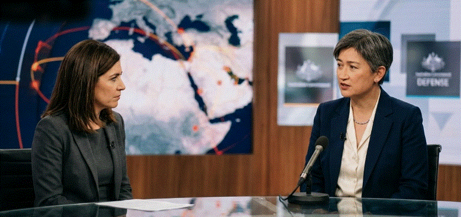 لقطة أفقية لمقابلة تلفزيونية في استوديو إخباري، تظهر فيها الإعلامية باتريشيا كارفيلاس (يسار) تنصت باهتمام لوزيرة الخارجية الأسترالية بيني وونغ (يمين) وهي تتحدث بجدية. الخلفية عبارة عن خريطة تفاعلية للشرق الأوسط مع شعارات الحكومة الأسترالية.