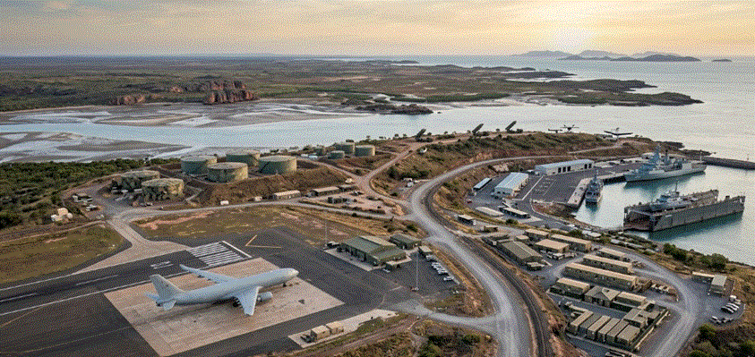 لقطة جوية بانورامية لقاعدة عسكرية متكاملة في شمال أستراليا، تظهر مدرج طائرات، وميناء بحري، وصهاريج تخزين الوقود، ومنشآت دعم لوجستي منتشرة على طول الساحل، تجسد مفهوم "المحرك الدفاعي" المقترح.