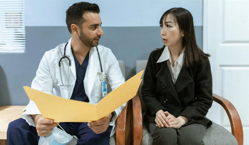 طبيب يناقش تشخيص اضطراب فرط الحركة وتشتت الانتباه مع مريضة بالغة داخل عيادة طبية