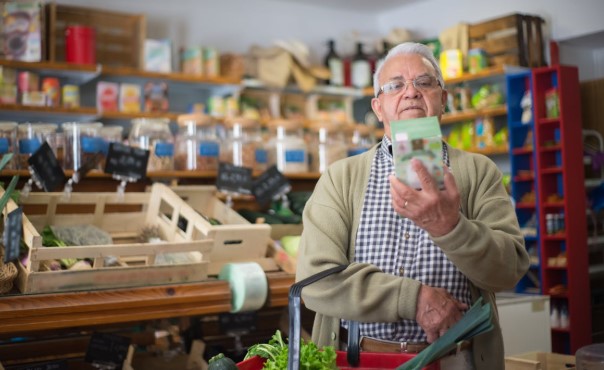 رجل يتفحص ملصق منتج غذائي داخل متجر في أستراليا لقراءة بلد المنشأ ومكونات المنتج