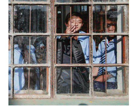 أطفال يقفون خلف نافذة قديمة وينظرون إلى الخارج في مشهد يعكس مشاعر العزلة والتهميش.