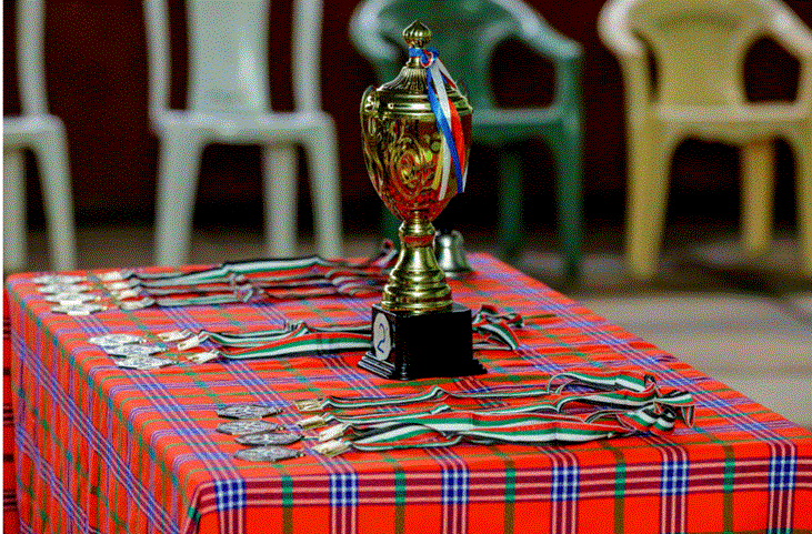 كأس بطولة ذهبي موضوع على طاولة مغطاة بميداليات وجوائز رياضية