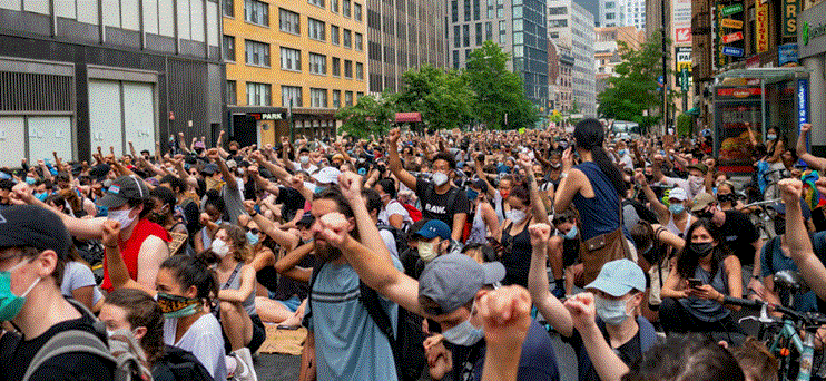 حشد كبير من المتظاهرين في شارع داخل مدينة يرفعون قبضاتهم في الهواء خلال احتجاج جماعي.