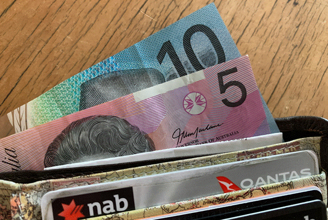 محفظة تحتوي على أوراق نقدية أسترالية وبطاقات بنكية، في إشارة إلى تكاليف المعيشة والضغوط المالية