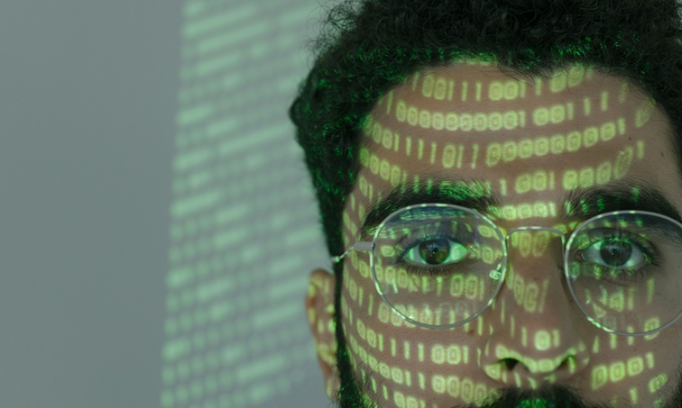 شخص تظهر على وجهه رموز برمجية رقمية في تعبير عن الذكاء الاصطناعي والأمن السيبراني.