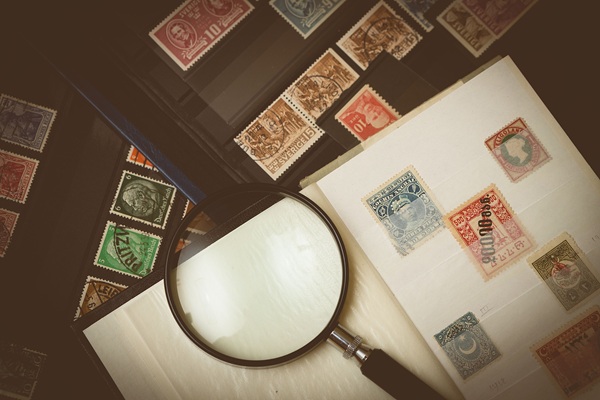مجموعة من الطوابع البريدية القديمة مع عدسة مكبرة ترمز إلى البريد التقليدي وارتفاع أسعار الطوابع في أستراليا.
