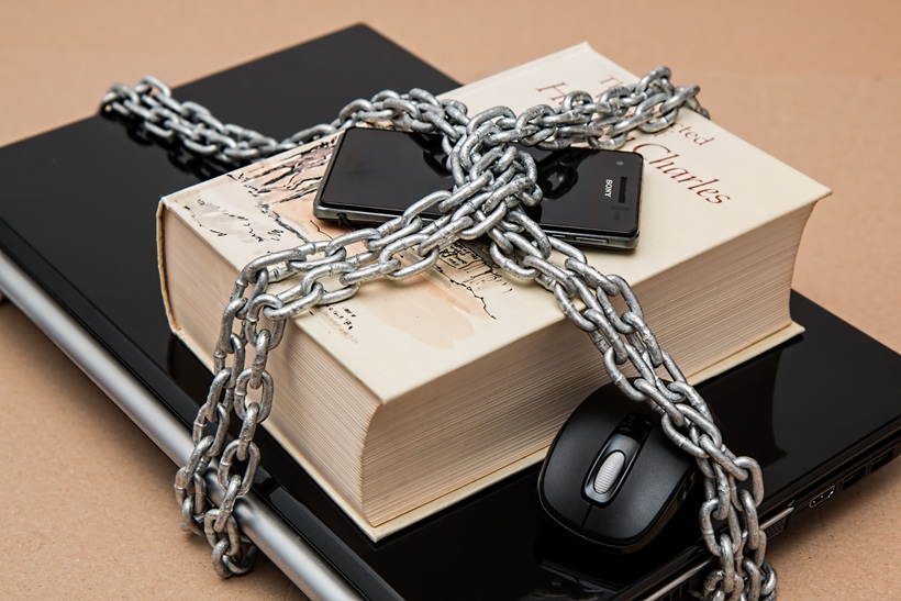 هاتف محمول وجهاز كمبيوتر محمول محاطان بسلاسل ترمز إلى حماية البيانات والخصوصية الرقمية.
